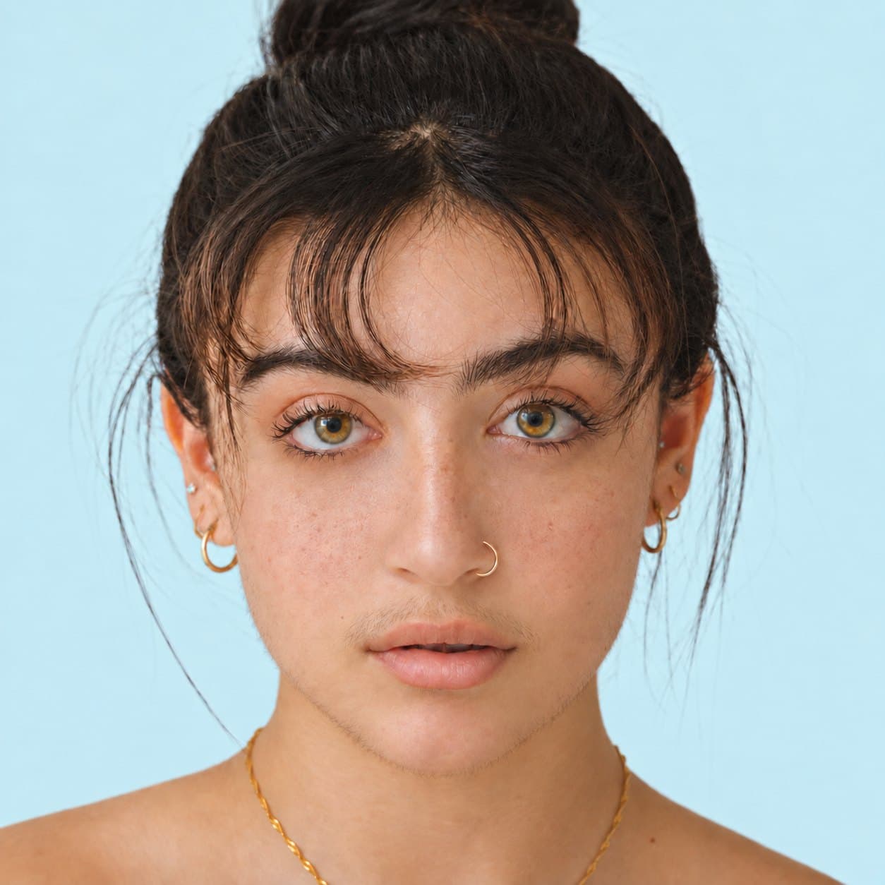 Portrait of a woman with clear skin against a light blue backdrop